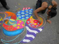Woman drawing chalk art on the sidewalk